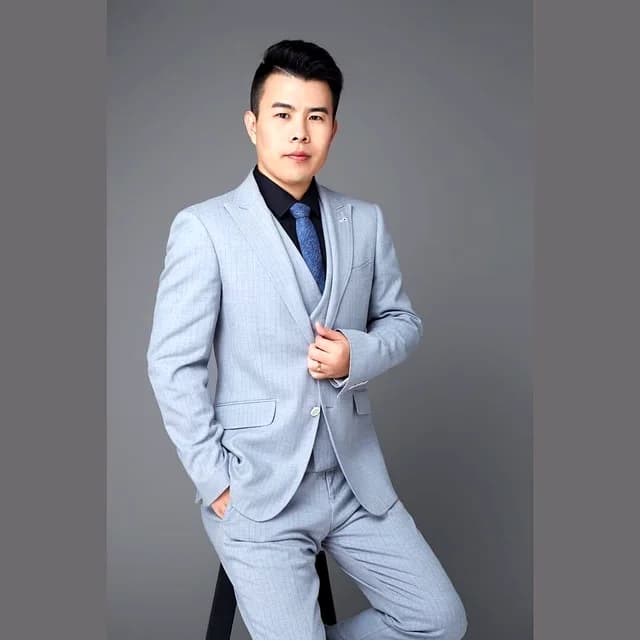 Rex Xu wearing a light grey suit against a grey studio background
